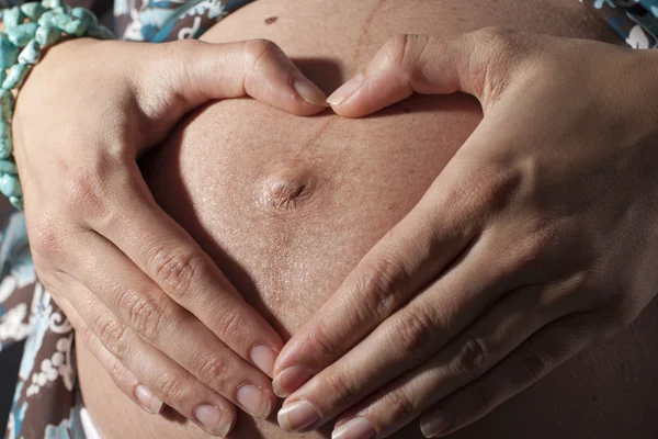 Pregnant woman's showing a heart — Stock Photo, Image