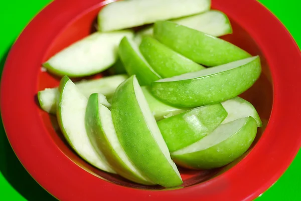 Nakrájené jablko kousky červené misky — Stock fotografie