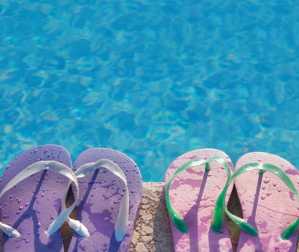 Flip flops near the swimming pool with blue water — Stock Photo, Image