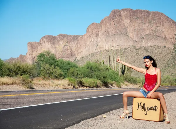孤独な砂漠の道路でヒッチハイクする若い女性 — ストック写真