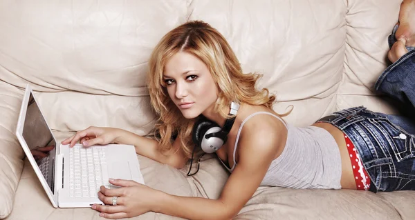 Flicka lyssna på musik medan du studerar på laptop. — Stockfoto