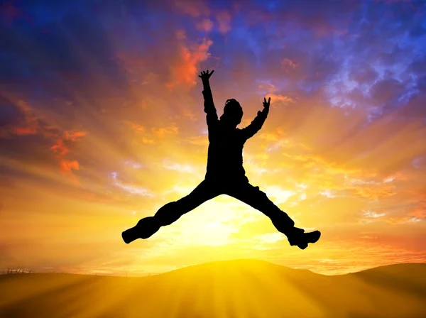 Hombre saltando sobre un fondo de puesta de sol — Foto de Stock