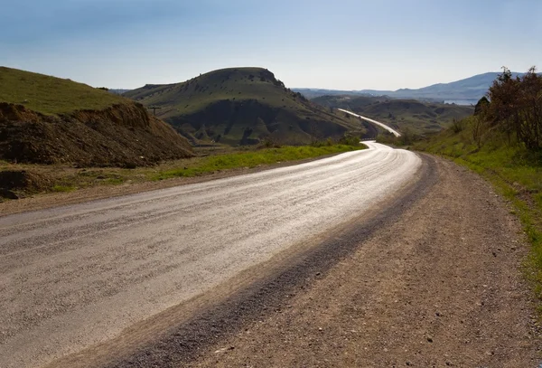 Asphalt road turn in a sunny valley — Stock Photo, Image