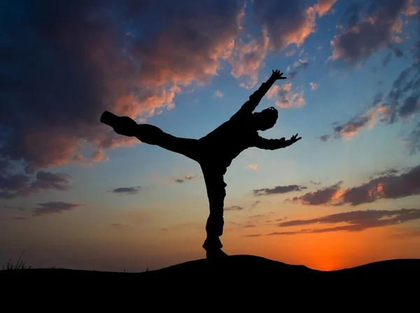 Man doing an exercise on a evening sky background — Stock Photo, Image