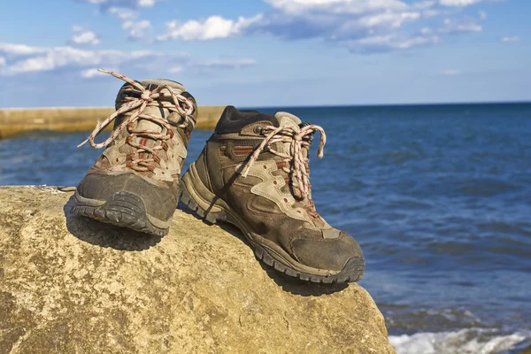 Par de botas turísticas en una costa del mar — Foto de Stock