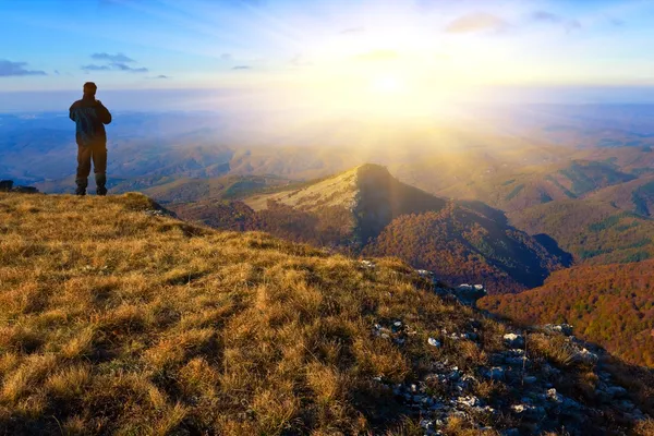 Viajante ficar perto da encosta da montanha ao pôr do sol — Fotografia de Stock