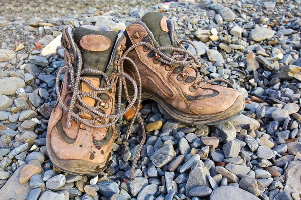 Pair of touristic boots on a sea pebbles — Stock Photo, Image