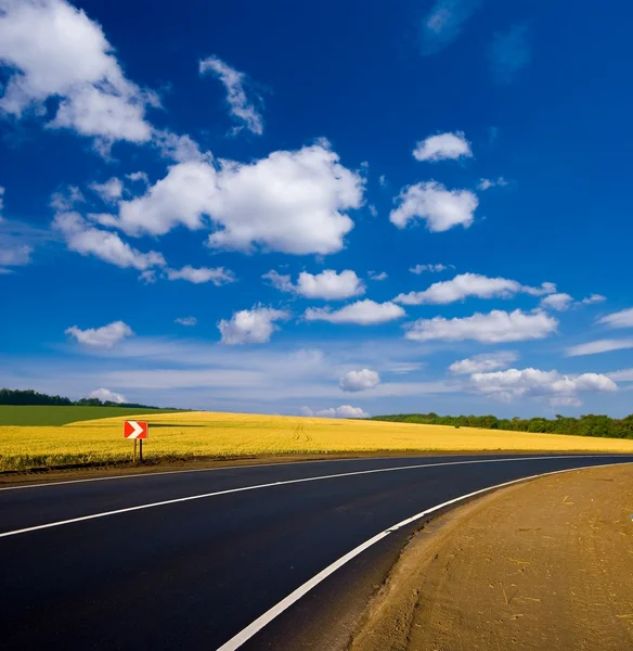 Asphalt road turn among a fields Royalty Free Stock Images