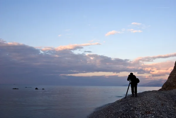 La silueta del fotógrafo en la costa de mar por la mañana —  Fotos de Stock