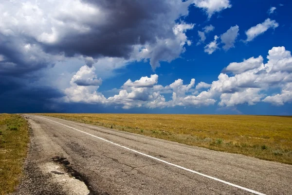 Estrada de asfalto distante e nuvens densas — Fotografia de Stock