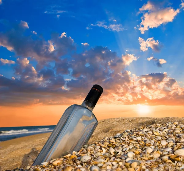 Flaske på en sjøkyst ved solnedgang – stockfoto