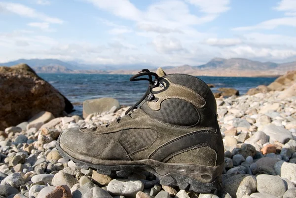 Туристический ботинок на берегу моря — стоковое фото