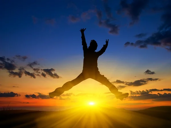 Homem silhueta pulando em um pôr do sol fundo — Fotografia de Stock
