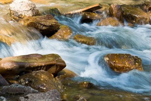 Pequeno fluxo de rio azul por umas pedras — Fotografia de Stock