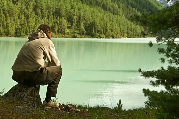 Człowiek siedzi w pobliżu jeziora — Zdjęcie stockowe