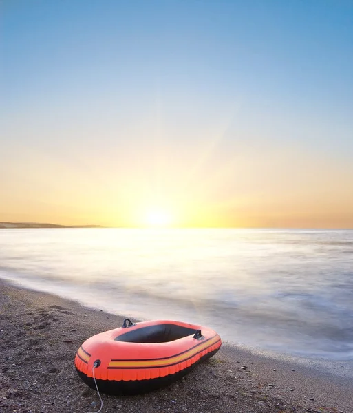 Kleines Schlauchboot an der Küste bei Sonnenaufgang — Stockfoto