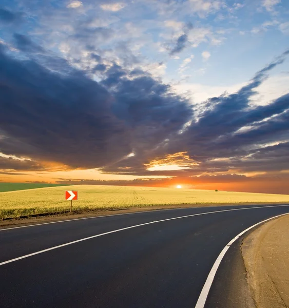Asfaltová silnice odbočit na západ slunce — Stock fotografie
