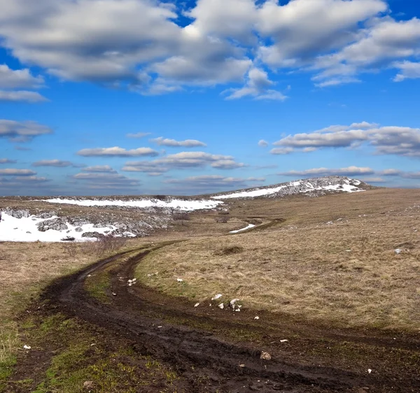 Špinavé silnici mezi kopci na jaře — Stock fotografie