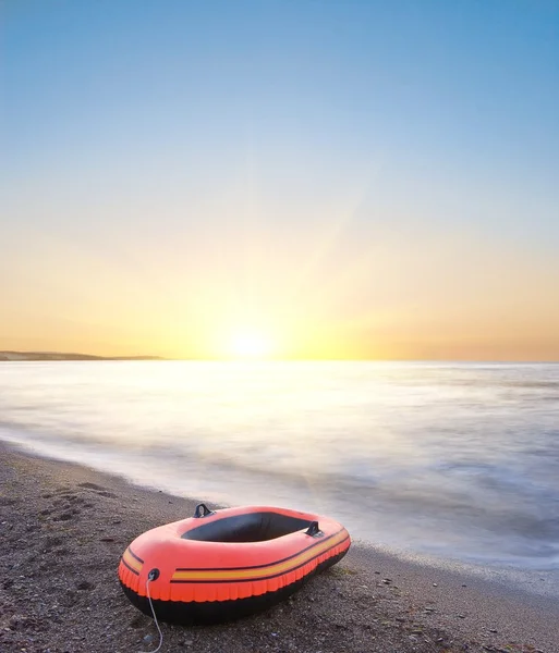 stock image Small inflatable boat on a sea coast at the sunrise