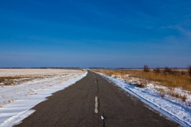 Asphalt road among a winter fields clipart
