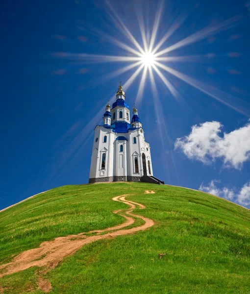Igreja cristã em uma colina verde sob um sol cintilante — Fotografia de Stock