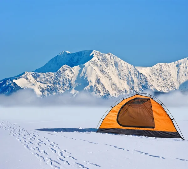 Оранжевая туристическая палатка перед ледяной стеной — стоковое фото