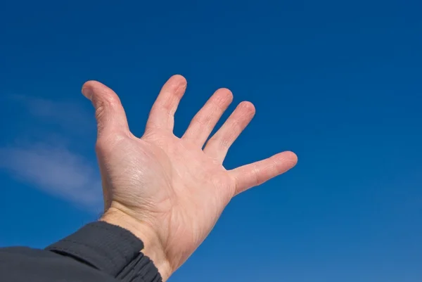Рука на голубом фоне неба — стоковое фото