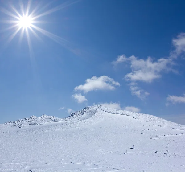 輝きの太陽の下での積雪山の頂上 ストックフォト