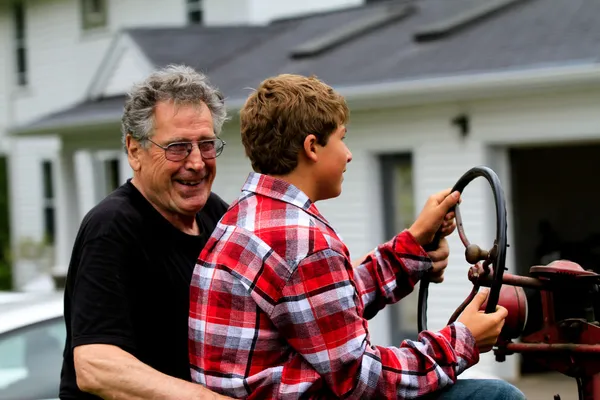 Farfar och sonson kör en traktor — Stockfoto