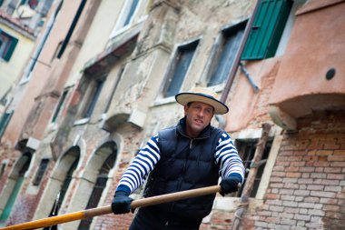 Gondolier navigates on the channel of Venice clipart