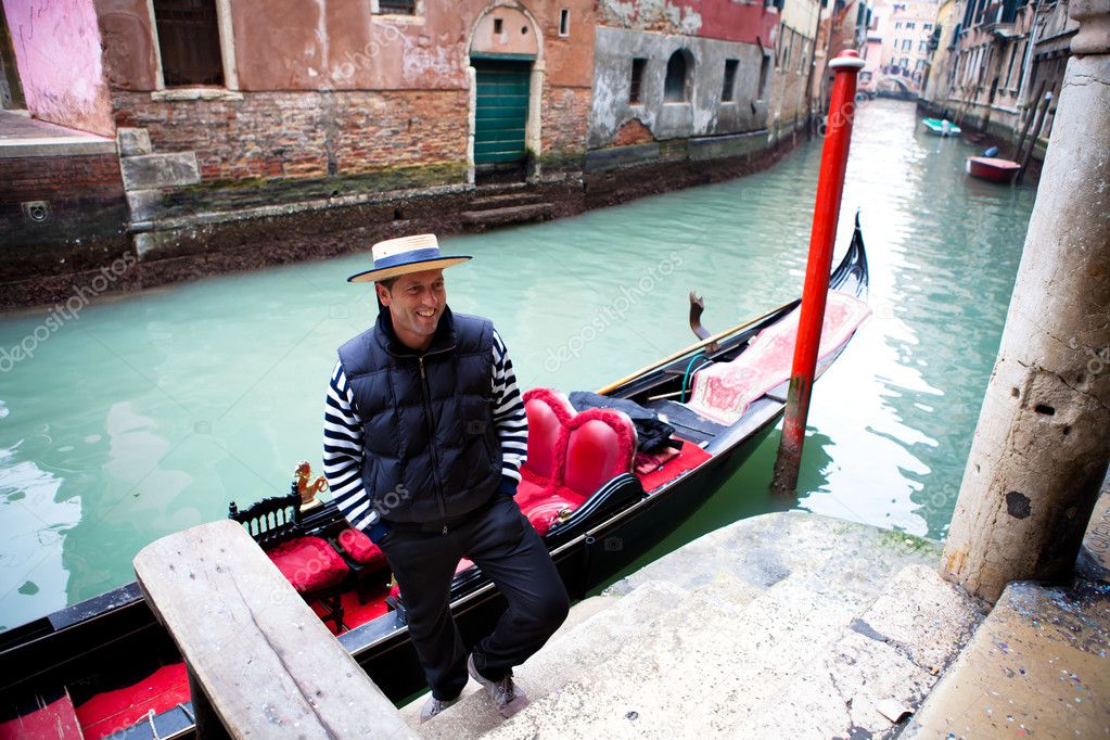 Gondolier welcoming tourist on a canal in Venice