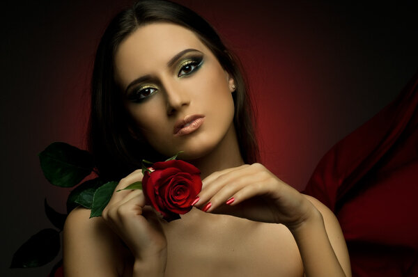 The very pretty woman on dark red background, with rose, sensual sexuality gaze...