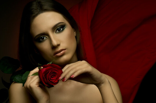 The very pretty woman on dark red background, with rose, sensual sexuality gaze...