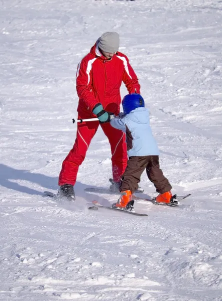 Instrutor ensina uma criança a andar de esquis — Fotografia de Stock