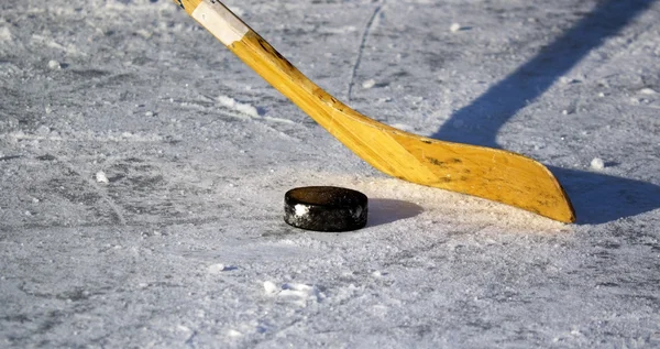 Palo de hockey y disco en el hielo — Foto de Stock