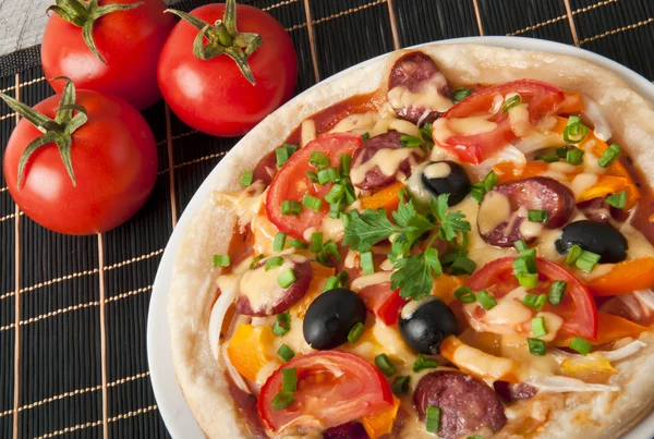 Closeup pizza s rajčaty, sýrem, černými olivami a papriky — Stock fotografie
