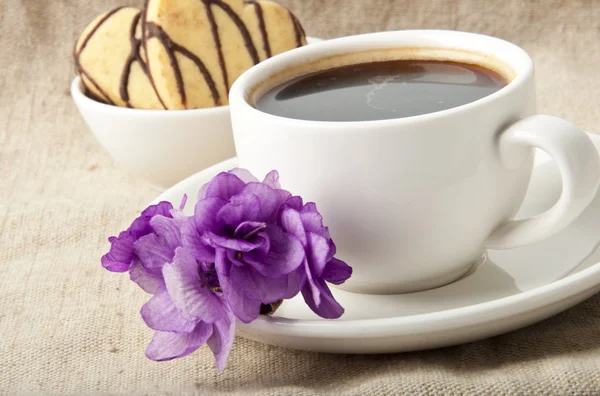 Чашка кофе и печенье с шоколадом и фиалкой — стоковое фото