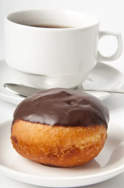 Пончик с шоколадом и чашкой чая на белом фоне — стоковое фото