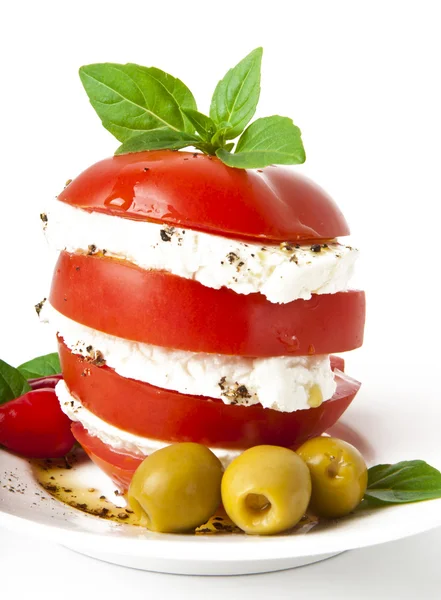 Rodajas de tomate y mozzarella decoradas con hojas de albahaca en un plato y whi — Foto de Stock