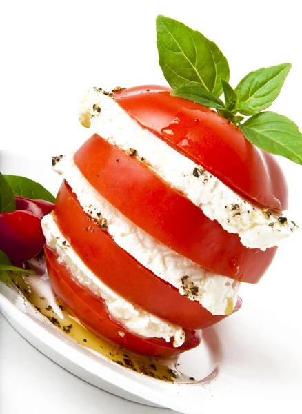 Tranches de tomate et mozzarella décorées avec des feuilles de basilic sur une assiette et whi — Photo