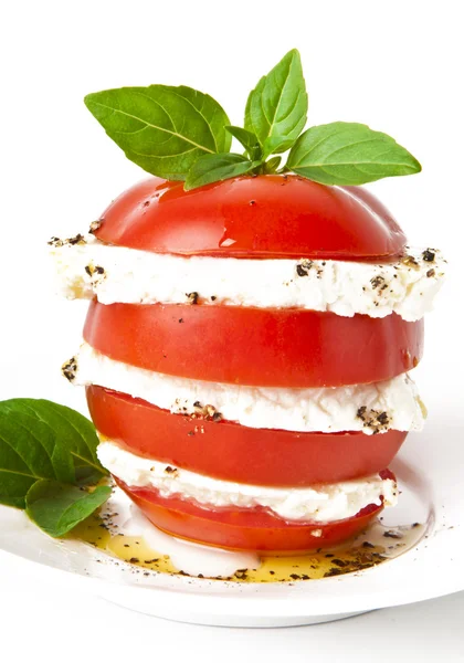 Tomato and mozzarella slices decorated with basil leaves on a plate and whi — Stock Photo, Image