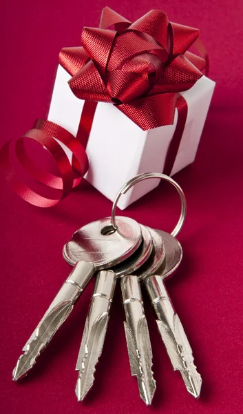 stock image Key with the gift box. House key on a red background.