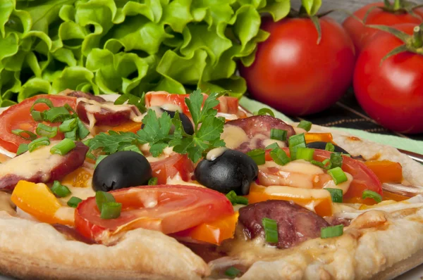 Fechar a piza com tomates, queijo, azeitonas pretas e pimentas . — Fotografia de Stock