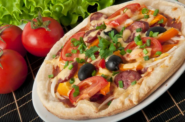 Primer plano de pizza con tomates, queso, aceitunas negras y pimientos . —  Fotos de Stock
