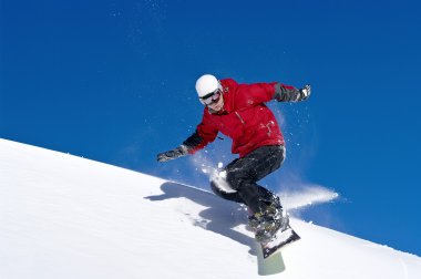 Snowboarder jumping through air with deep blue sky clipart