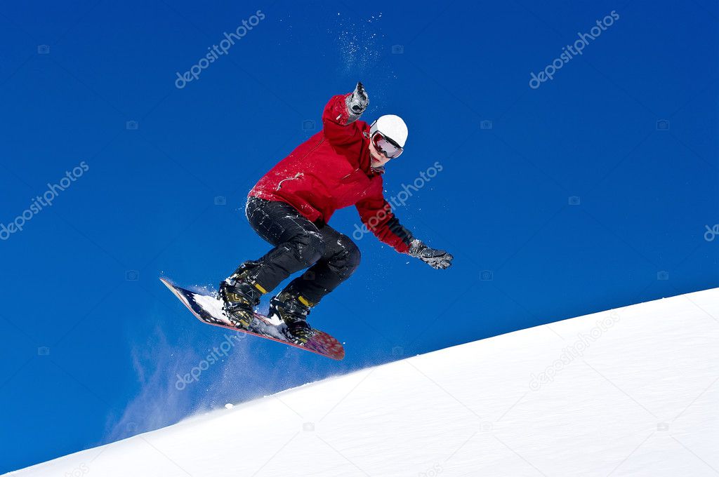Snowboarder jumping through air with deep blue sky