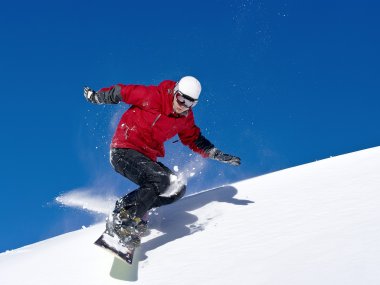 Snowboarder jumping through air with deep blue sky clipart