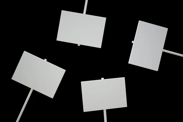 Quatro sinais em branco isolados em uma superfície preta — Fotografia de Stock