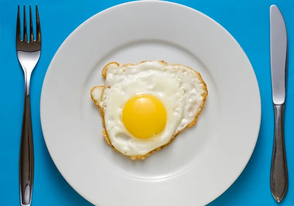 Fried egg on a plate with flatware — Stock Photo, Image