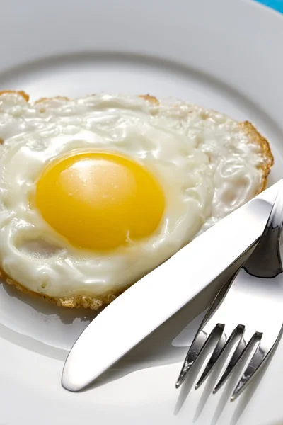 Uovo fritto su un piatto con posate — Foto Stock